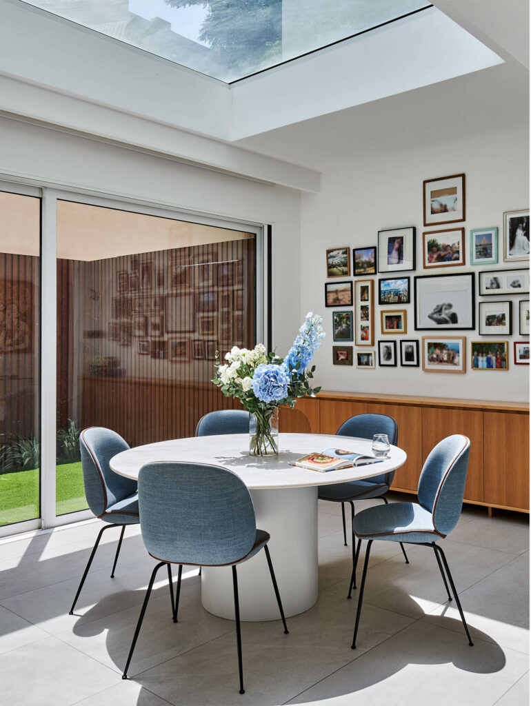 a white round table with blue chairs and a vase with blue flowers