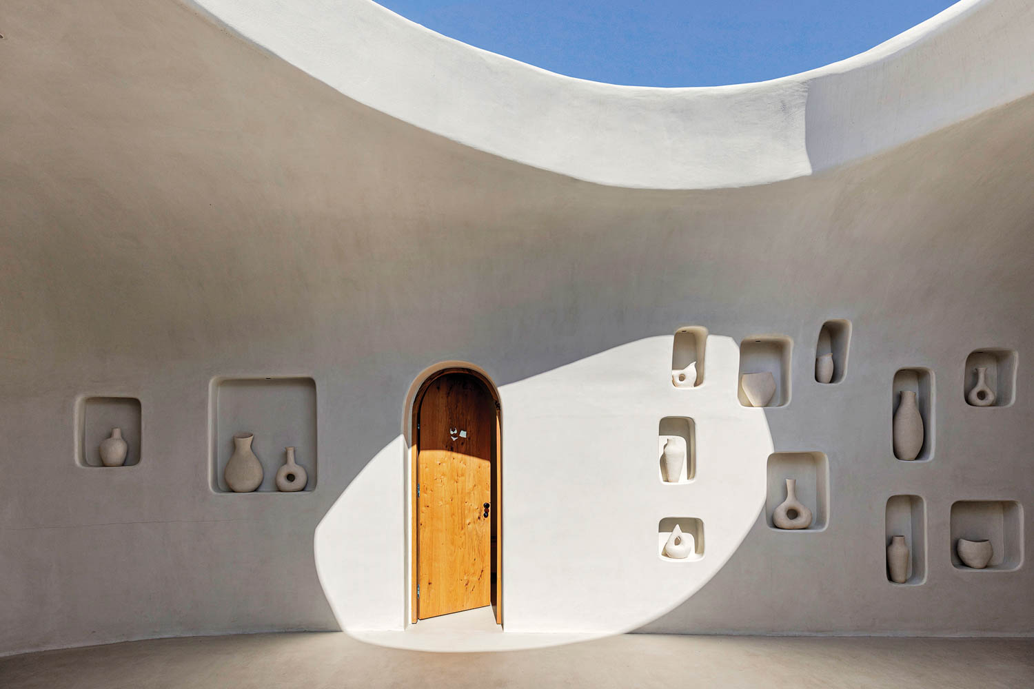 an exterior of a Greek beach club resort with stone walls