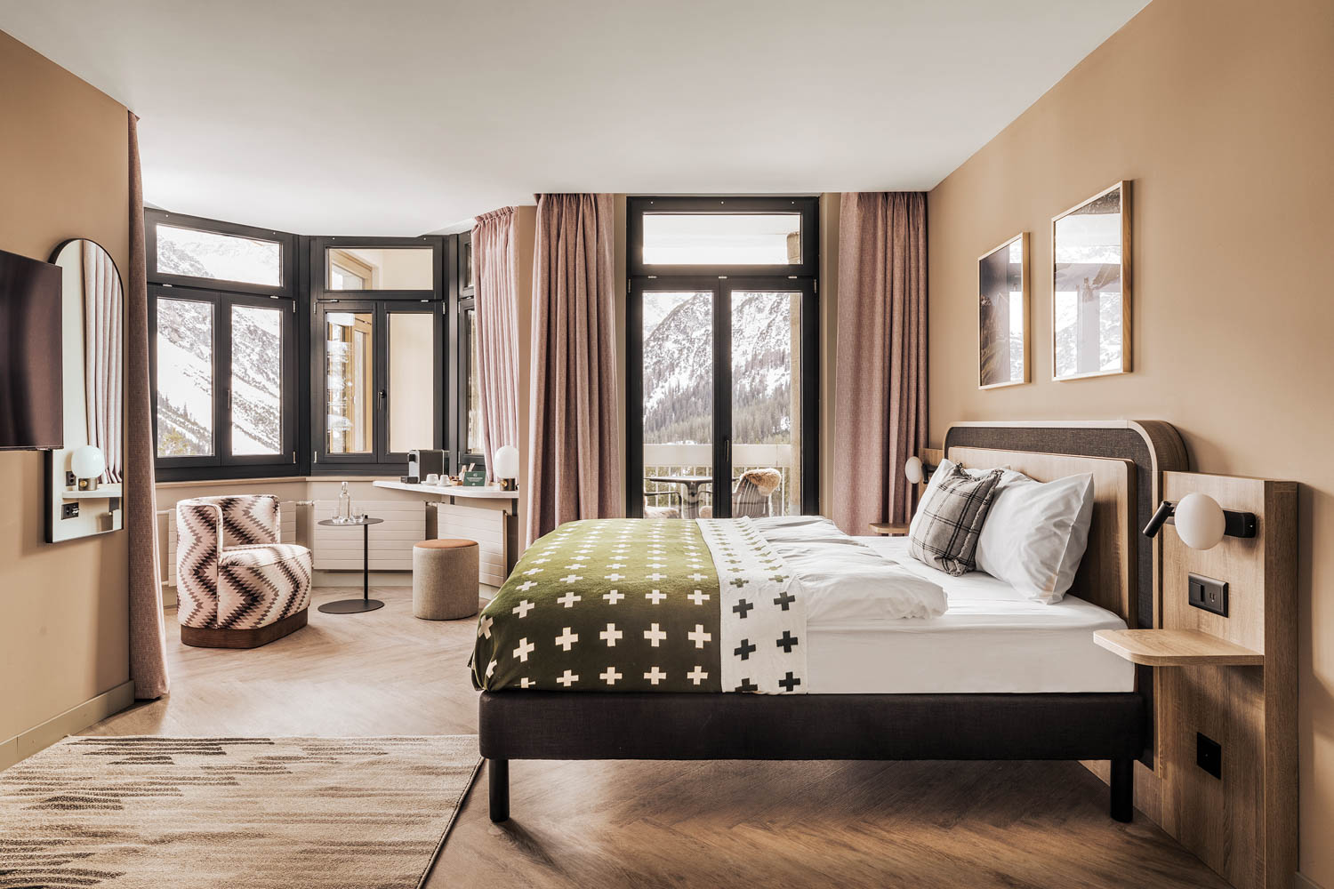 a guest room in a Swiss resort, surrounded by large glass windows overlooking snowy mountains